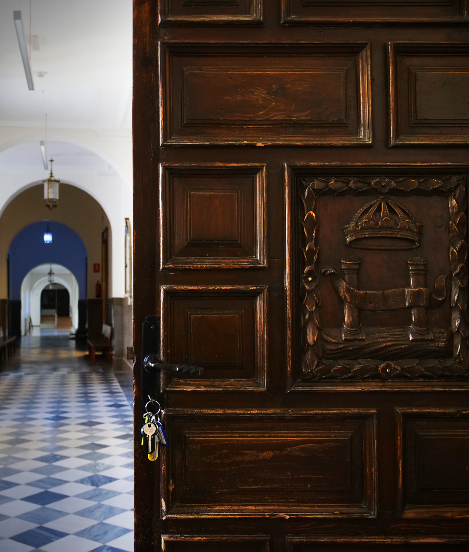 Puerta de madera abierta que da a un pasillo de la Facultad de Derecho